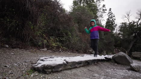 happy child balancing on icy tree trunk, playful winter day in argentine forest
