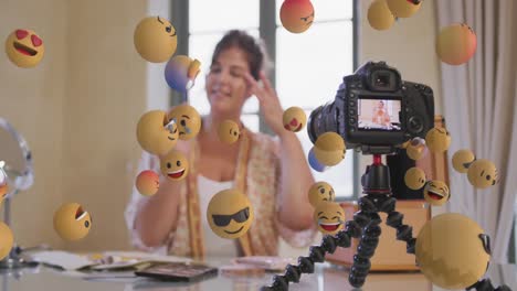 animación de iconos emoji sobre vlogger femenino en el visor de la cámara grabando vlog en casa