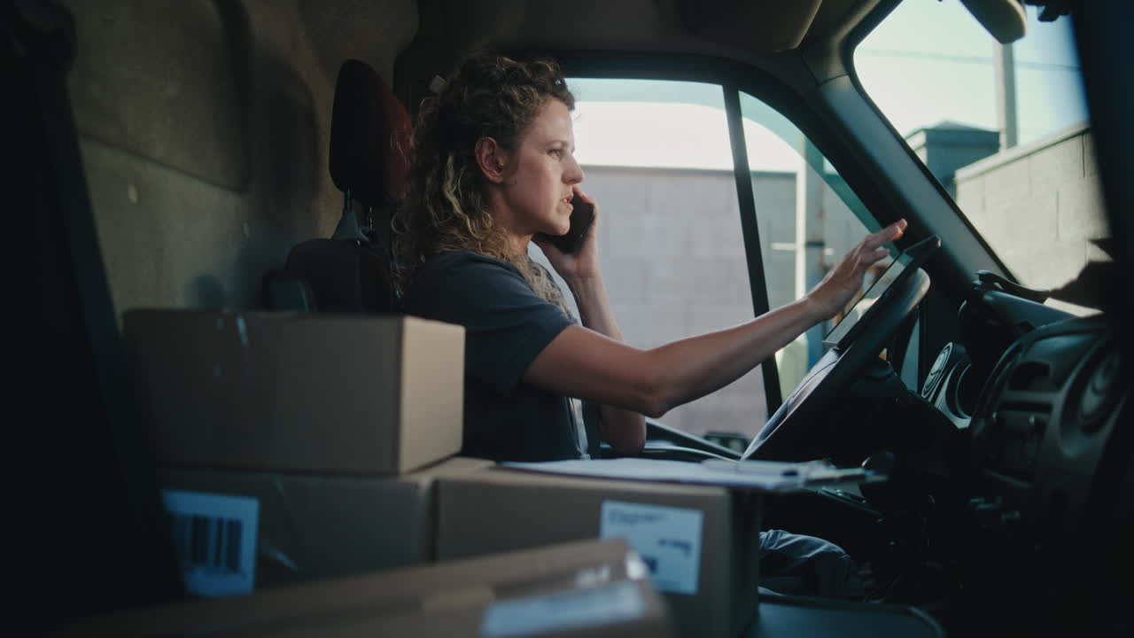 Female Delivery Driver Talking on Phone in Van with Packages