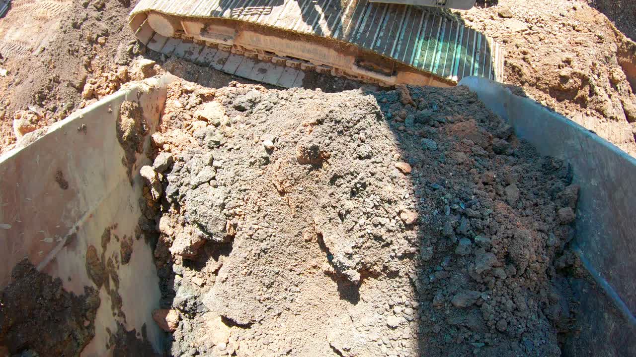 pov del cubo de la excavadora lleno de tierra, dejando caer tierra en el sitio de construcción