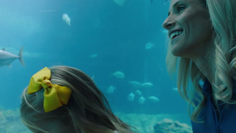 mother at child in aquarium looking at beautiful fish swimming in tank little girl watching marine animals with curiosity having fun learning about marine life with mom in oceanarium