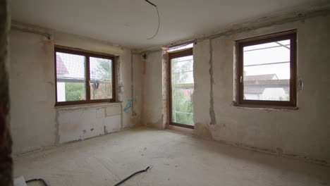 wide shot on a construction site, looking into the corner of a room, three windows visible, looking outside