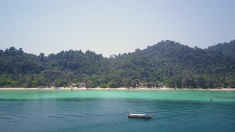 Aerial-tracking-shot-of-lush-island-with-beach-and-beautiful-waters-in-Thailand