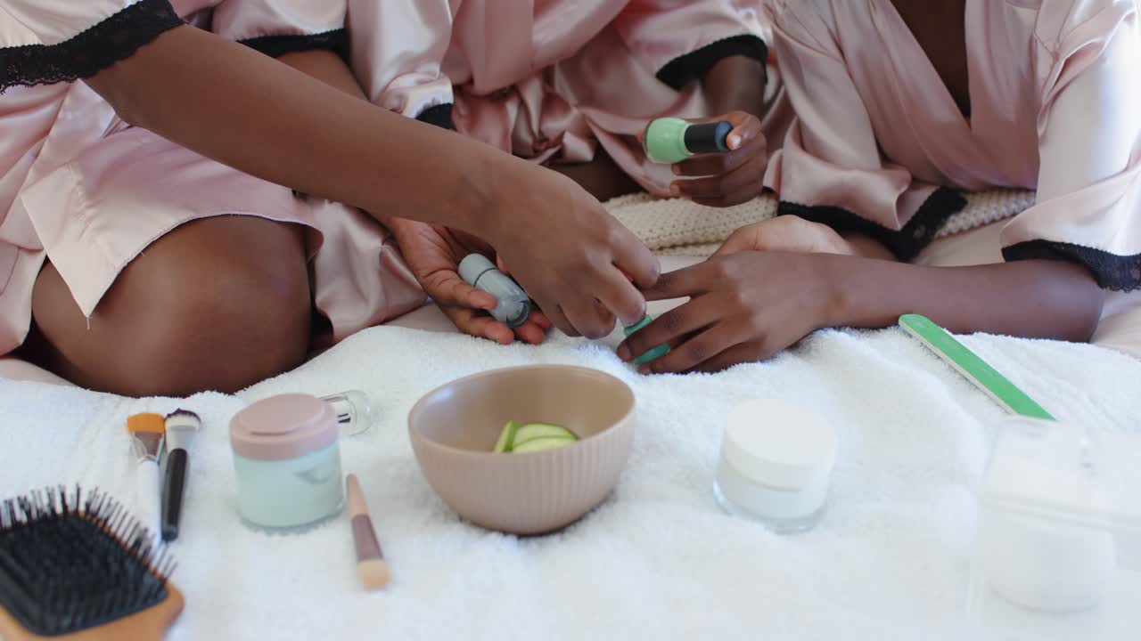 Mother guiding child's hands to open turquoise bottle, applying manicure on white bedspread