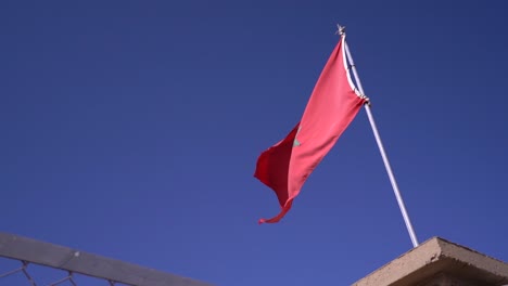 bandera marroquí ondeando en un área restringida, contra un cielo azul despejado