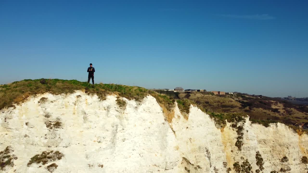 Coastal cliff landscape with a man standing on the edge