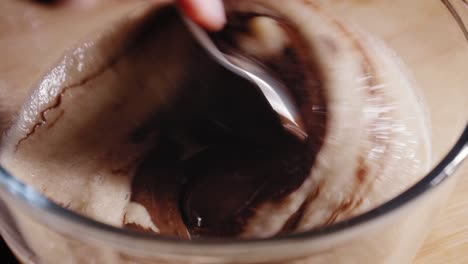 mixing blended bananas and melted dark chocolate in a bowl with spoon