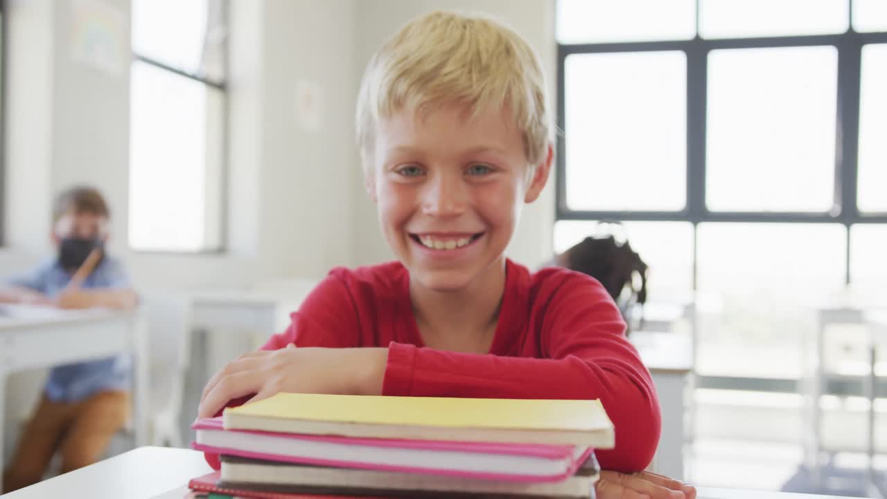 Video von glücklichem kaukasischem Jungen, der am Schultisch sitzt