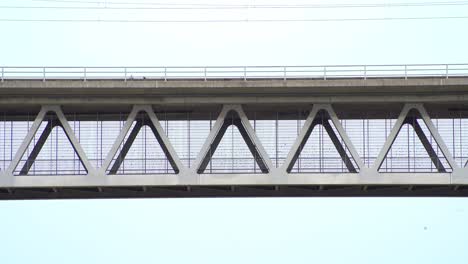 dos palomas están sentadas en un puente ferroviario de construcción de acero y vuelan lejos