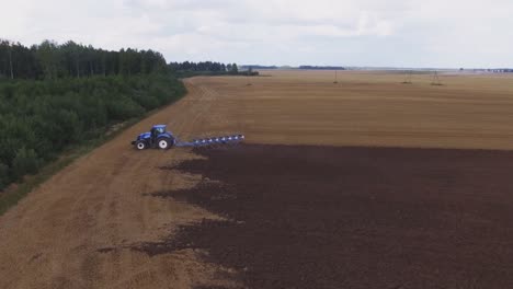 blue modern plowing tractor working in the field-6