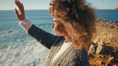 curly woman warming sunlight at windy shore closeup. happy lady looking camera