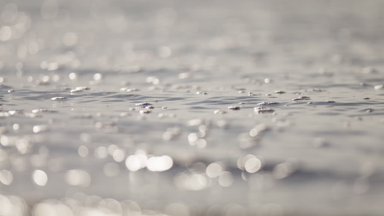 Soft sparkling highlights move across water bubbling surface at sunset creating delicate shimmering texture, natural backdrop