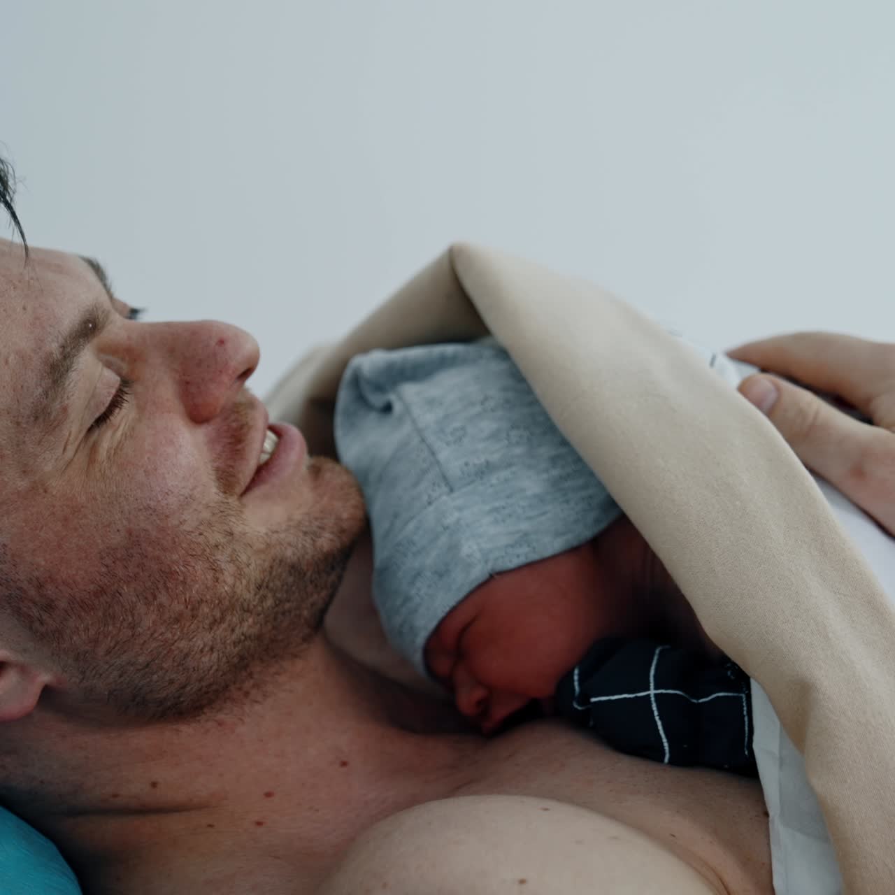 Skin to skin contact of a newborn with a father. Man is smiling happily to hold his baby for the first time. Close up