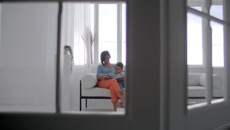 Mother-Sitting-With-Son-Reading-Story-Indoors