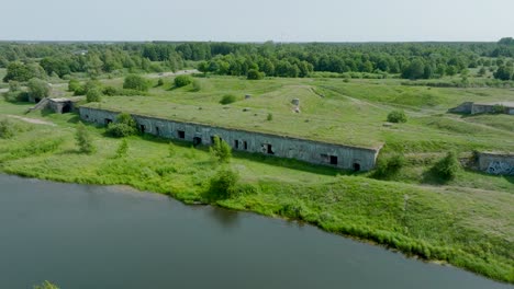 aerial establishing view of abandoned historical concrete seaside fortification buildings, southern forts near the beach of baltic sea in liepaja, sunny summer day, ascending drone dolly shot