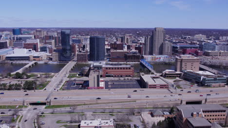 Wide-aerial-pan-of-trafficked-highway,-river-and-Grand-Rapids-skyline