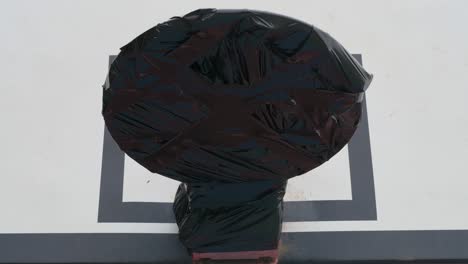 a low angle basketball hoop fully covered with black tape to avoid people to play and use the playground during covid-19 coronavirus outbreak and restrictions