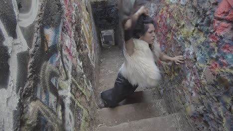 an interpretive dancer in slow motion flips her long dark hair around in circles and then crawls up towards the camera, reaching at the lens