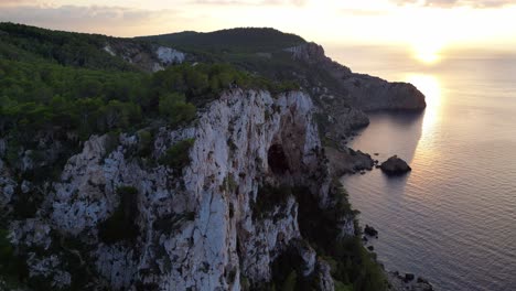 Ibiza-sunset-overlooking-a-rocky-sea-cliff-and-calm-ocean