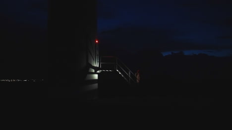 Static-view-of-sinister-hooded-man-climbing-the-metal-stairs-from-one-door-to-the-other-dimension-at-night