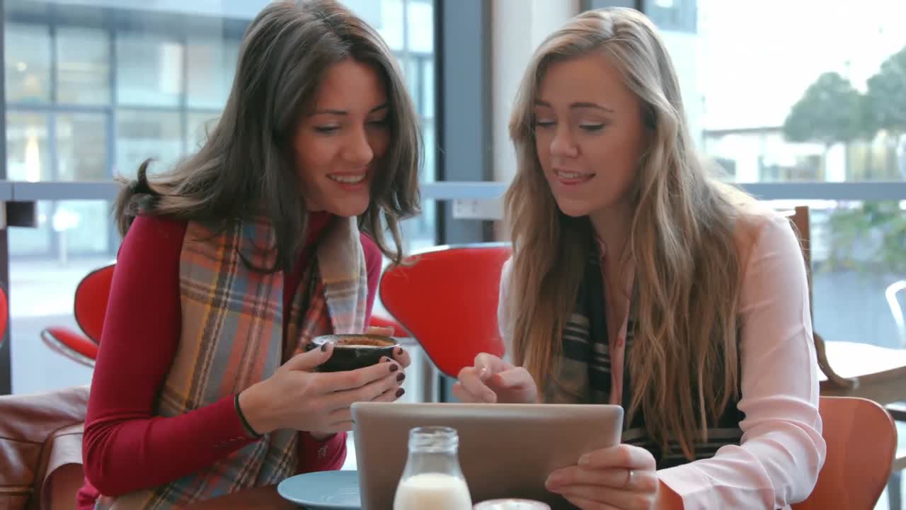 Pretty friends enjoying coffee in cafe