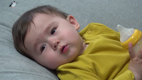 Baby-boy-doesn't-want-to-drink-milk-anymore-so-he-plays-with-the-bottle-in-his-hands