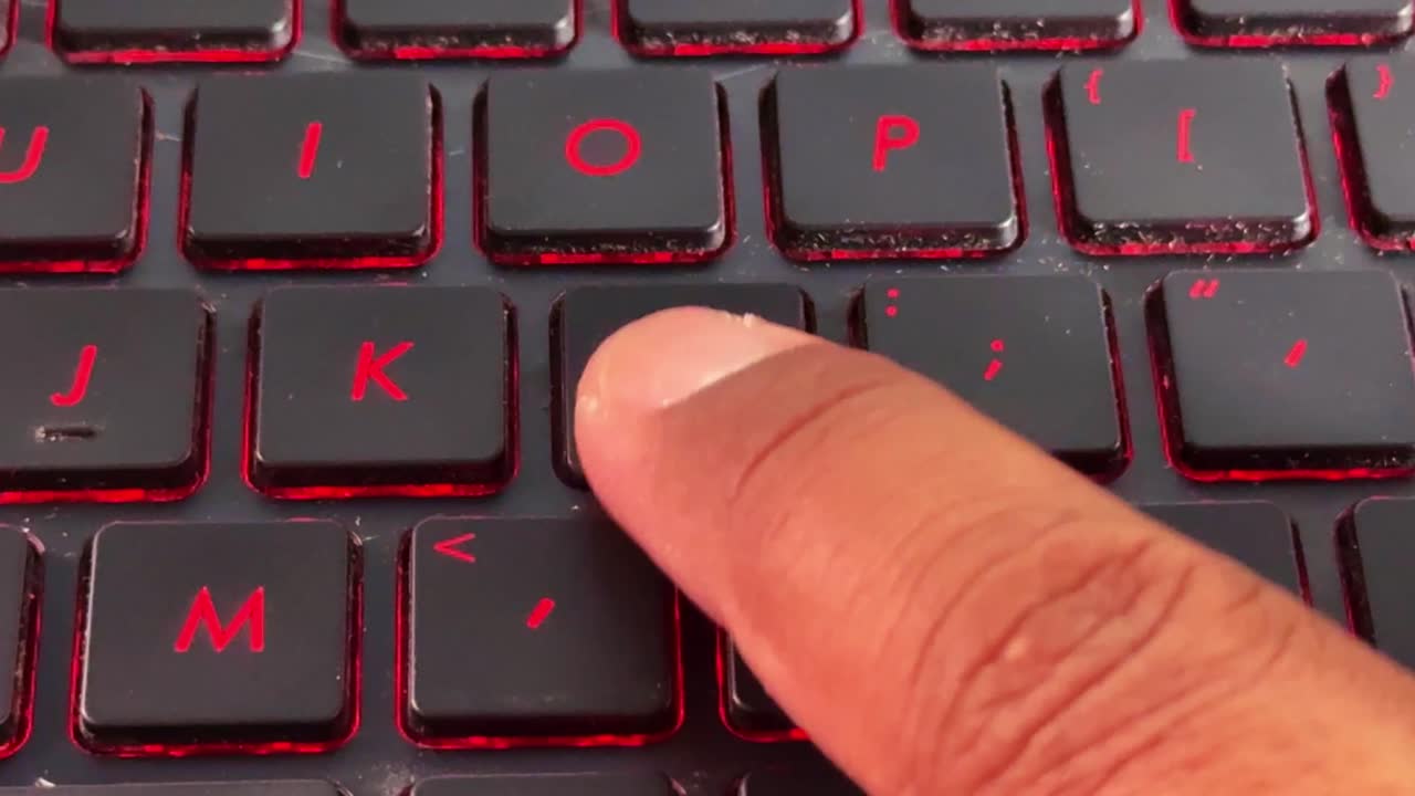 Nærbillede af finger, der trykker på "L" på et bærbart tastatur, digital indtastning, moderne teknologi og kontorarbejdsgang