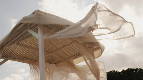 tent from the sun on the beach fabric fluttering in the wind at sunset comfortable rest concept slow