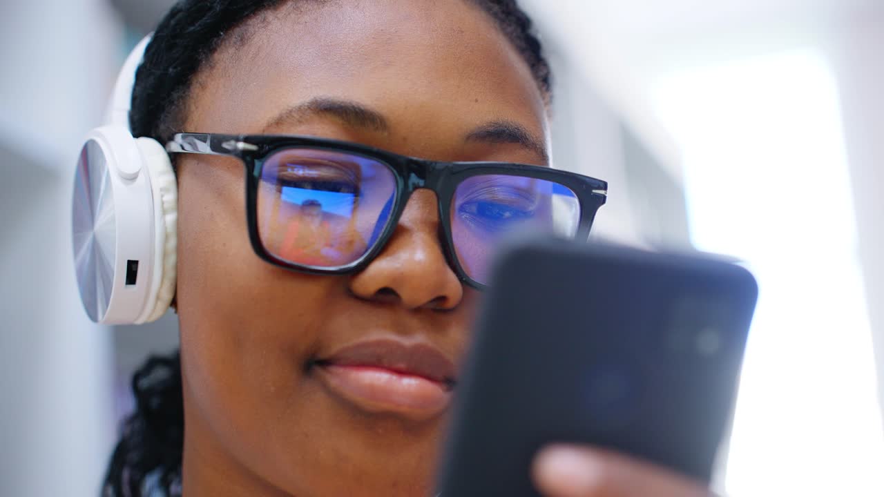 Young Black Woman Wearing Headphones and Using Smartphone