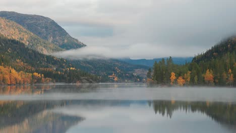 Forest-covered-mountains-and-clouded-sky-reflected-in-the-still-mirrorlike-waters-of-the-lake