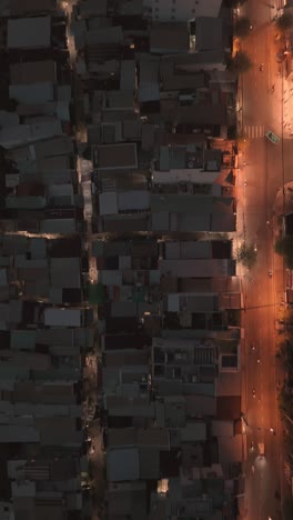 To-down-view-of-urban-Saigon,-Ho-Chi-Minh-City-at-night-featuring-rooftops,-road-with-traffic