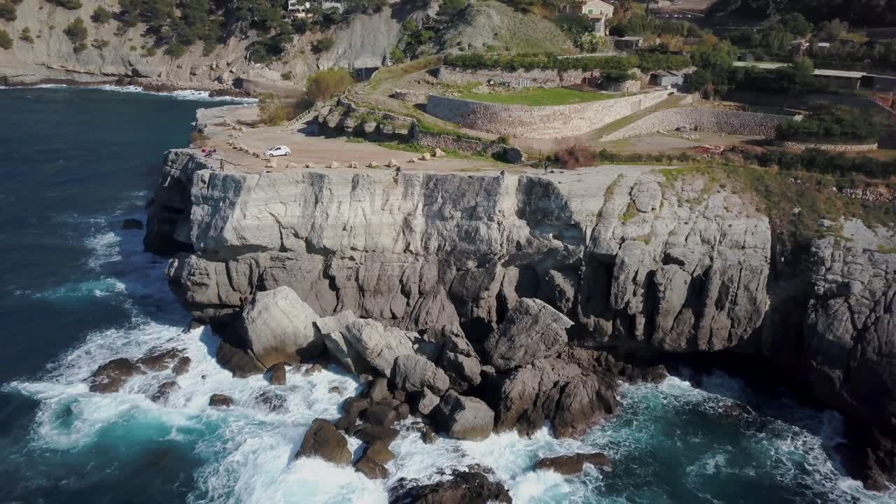 impresionantes imágenes de drones de 4k de la costa oeste de mallorca -serra de tramuntana- gente sentada en un acantilado en cala banyalbufar