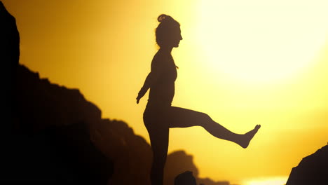 woman practicing yoga at sunset on rocks