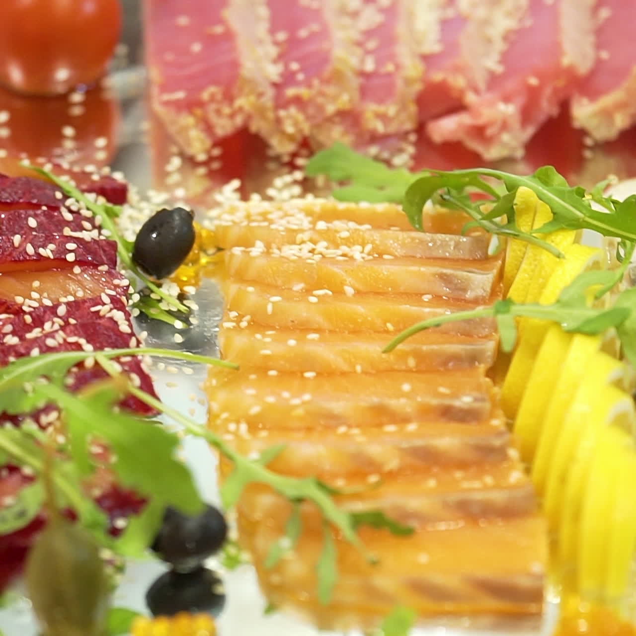 Serving sliced with dried and smoked meat, red fish fillet, hard cheese decorated with olives, red caviar, cherry tomatoes, lemon slices and cilantro leaves nearby. Close-up.