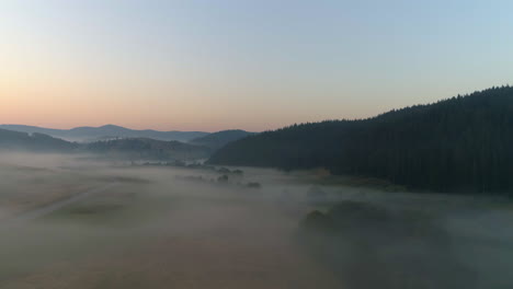 flying over early morning over a hilly field of fog