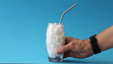 hand holding a glass full of sugar cubes