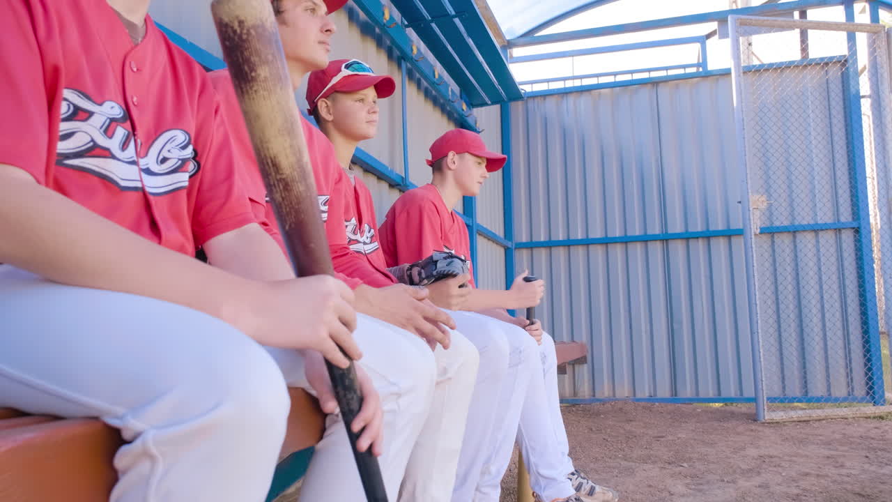 Young baseball players eagerly awaiting their chance to play in the dugout during games