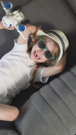 cheerful girl laughs while little brother playing with airplane toy in room. siblings rest after summer activity on vacation upper close view