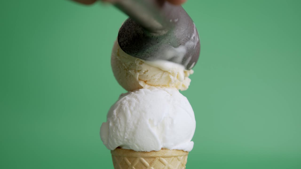 las manos recogen el helado de vainilla en la parte superior del coco en conos.