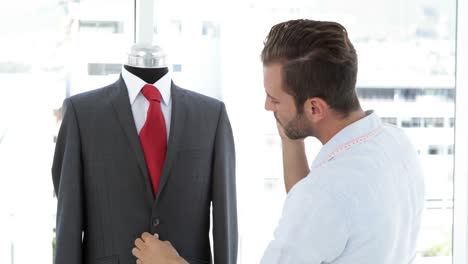 Handsome-tailor-touching-suit-and-talking-on-phone