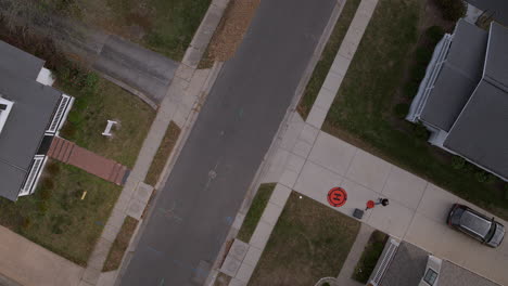 Vista-Aérea-Del-Piloto-De-Drones-En-La-Entrada-De-Los-Suburbios-Con-Una-Inclinación-Hacia-El-Cielo-Y-En-El-Horizonte-Mientras-Desciende