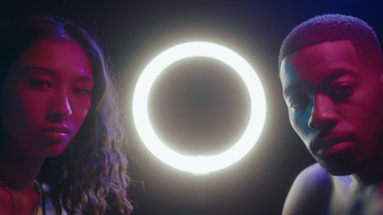 Young Man and Woman Posing with Ring Light in Neon