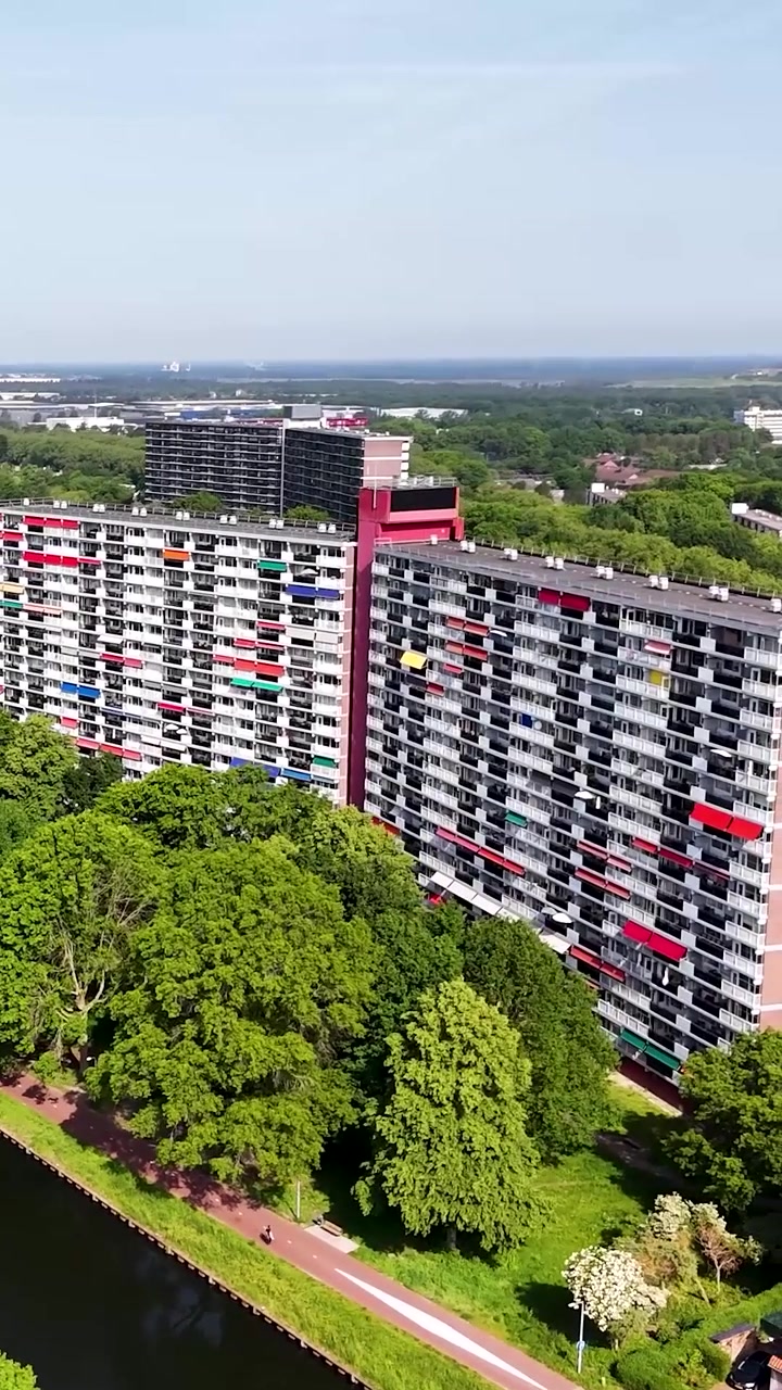 Ripresa con drone di un vivace complesso di appartamenti circondato da alberi verdi e un canale.
