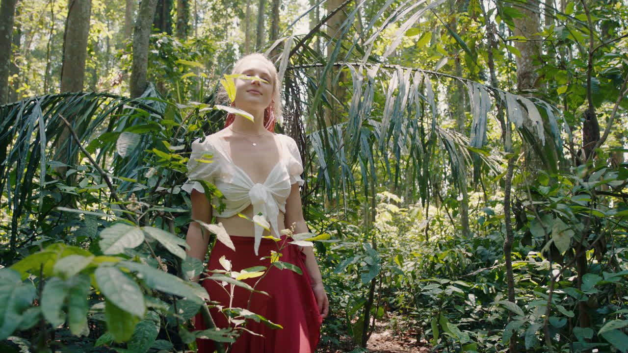 아름다운 여성이 숲을  ⁇ 고 울창한 열대 우림을 탐험하고 혼자 자연의 아름다움을 즐기고 영적 여정에서 길을 잃습니다.