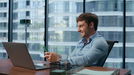 Hombre-Sonriente-Leyendo-Buenas-Noticias-Primer-Plano-De-La-Oficina-Del-Teléfono-Móvil.-Empresario-Riendo