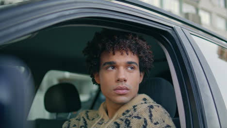 young driver sitting car steering wheel looking through window on city closeup