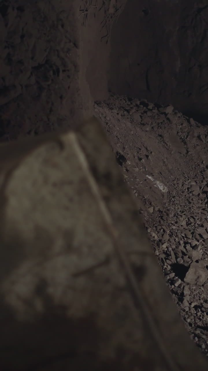Large dipper of heavy machinery with big wheels scooping up ore in dark mine. Professional vehicle helps to extract and transport minerals closeup