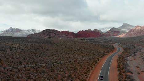 aerial drone shot along a small road with snow flurries and mountains in the background