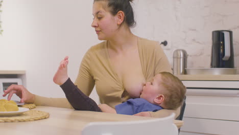 Young-Mother-Working-With-Laptop-Computer-And-Breastfeeding-Her-Baby-Boy-At-Home-2