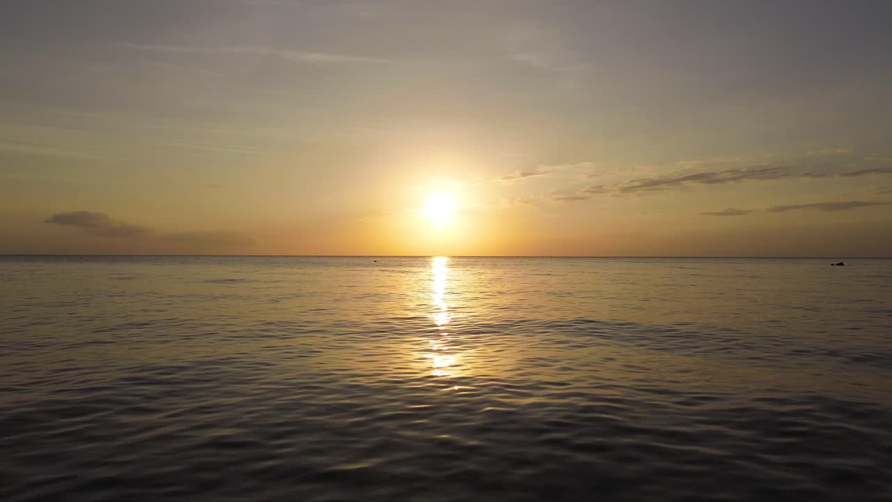 Aerial drone view of tropical coastline at sunset on Siquijor island Philippines featuring warm golden hour light calm ocean reflections and peaceful natural scenery ideal for travel and destination